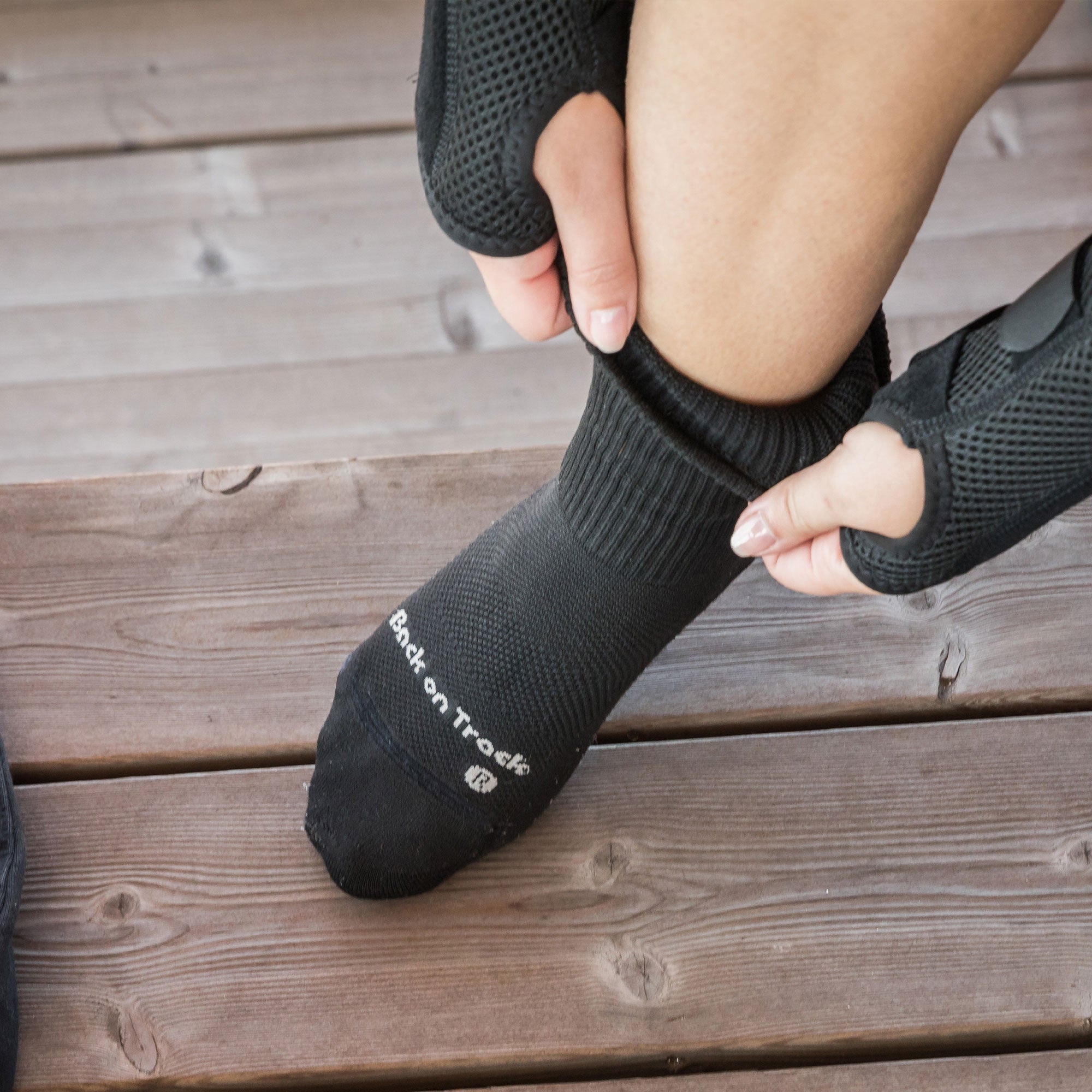 BILLIE Socke beim Anziehen auf einer Holzbank